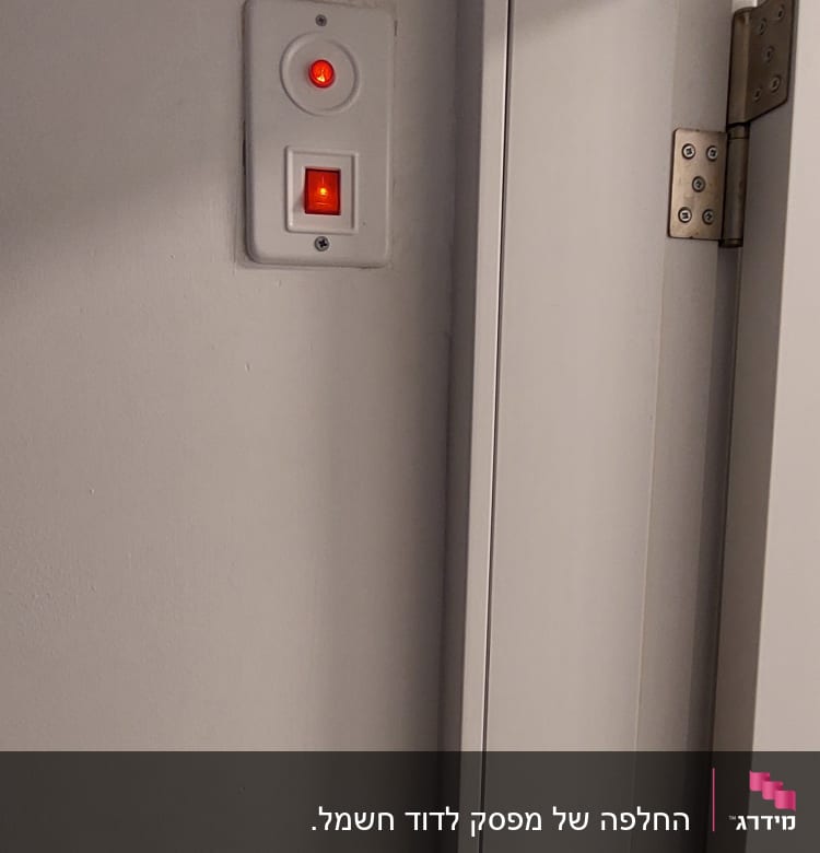 מתג חשמלי עם נורית חיווי אדומה על קיר